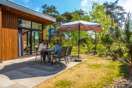 Couple at a table in the garden of a holiday home at the EuroParcs De Wije Werelt holiday park