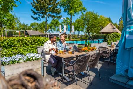 Couple eats on the terrace of the restaurant at holiday park EuroParcs De Wije Werelt