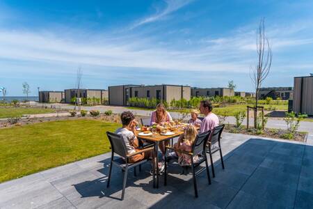 Family eats at a table in the garden of a home at the EuroParcs Enkhuizer Strand holiday park