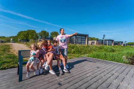 The family is sitting on a jetty on the IJsselmeer at the EuroParcs Enkhuizer Strand holiday park