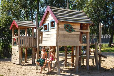 Two children at wooden playground equipment in the playground of holiday park EuroParcs Gulperberg