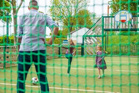 Family playing football on the multifunctional playing field of holiday park EuroParcs Gulperberg