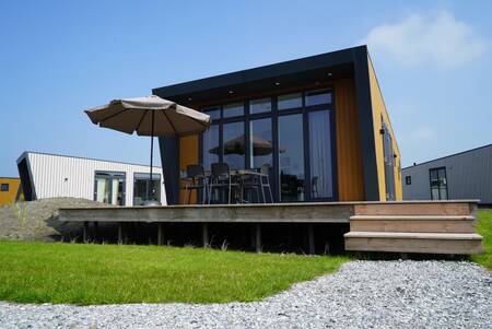 Holiday home with garden furniture on a wooden deck at the EuroParcs Hindeloopen holiday park