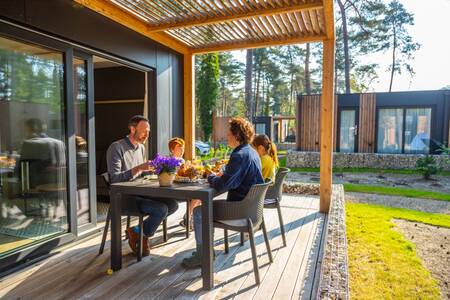 The family eats on the veranda of a chalet at the EuroParcs Hoge Kempen holiday park