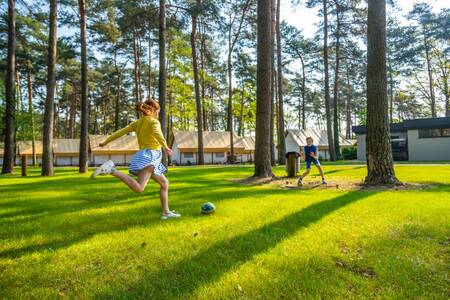 Children play football in front of holiday homes at EuroParcs Hoge Kempen
