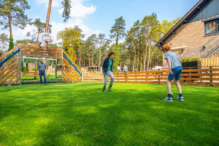 Family playing football on the playing field at the EuroParcs Hoge Kempen holiday park