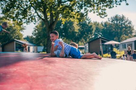 2 children play on the air trampoline in the playground at the EuroParcs Kaatsheuvel holiday park