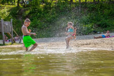 Children play in the water of the beach pool of holiday park EuroParcs Maasduinen