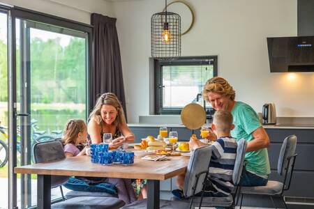 Family having breakfast in the kitchen of a holiday home at the EuroParcs Maasduinen holiday park