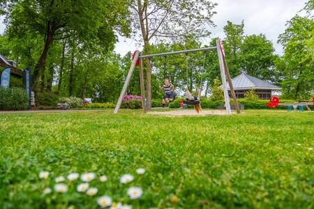 Children on the swing in a playground at the EuroParcs Maasduinen holiday park