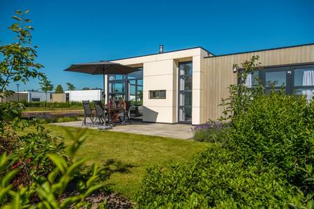 People are sitting on garden furniture in the garden of a chalet at the EuroParcs Marina Strandbad