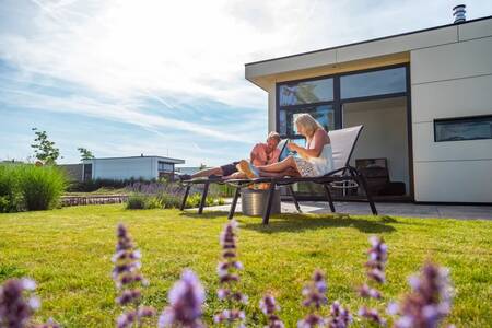A couple relaxes in the garden of a holiday home at the EuroParcs Marina Strandbad holiday park