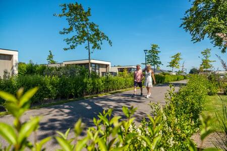 Couple walks in front of holiday homes at the EuroParcs Marina Strandbad holiday park