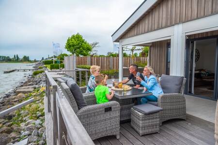 The family eats on the veranda of a waterside chalet at the EuroParcs Markermeer holiday park