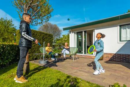 Family relaxing in the garden of a holiday home at the EuroParcs Molengroet holiday park