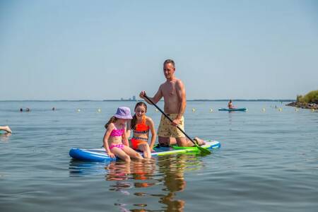 Family on a supboard on the Markermeer at the EuroParcs Poort van Amsterdam holiday park