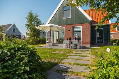 Family at the table in the garden of a holiday home at EuroParcs Poort van Amsterdam