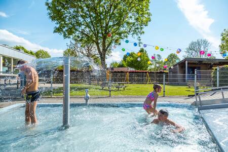 Children splash in the outdoor pool of holiday park EuroParcs Poort van Maastricht