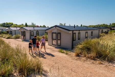 The family walks between holiday homes at the EuroParcs Poort van Zeeland holiday park