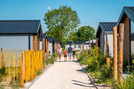 Family walks on a path between holiday homes at the EuroParcs Poort van Zeeland holiday park