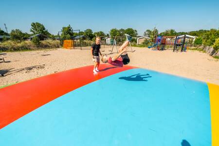 Children jump on the air trampoline in the playground at EuroParcs Poort van Zeeland holiday park