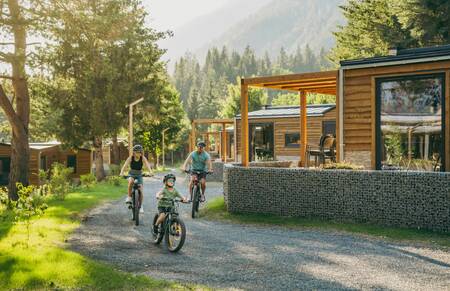 Family cycles along an avenue past holiday homes at the EuroParcs Pressegger See holiday park