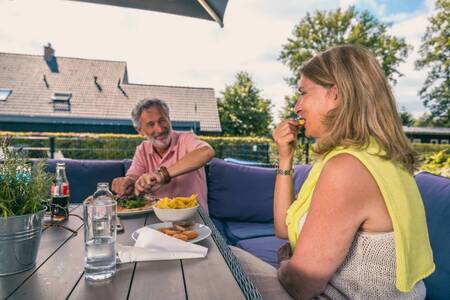 Couple eating on the terrace of the snack bar at the EuroParcs Reestervallei holiday park
