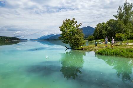 People walk along the Feistritzer Stausee, the reservoir on which EuroParcs Rosental is located