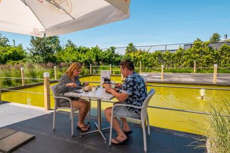 Couple eats on the terrace of the restaurant of the EuroParcs Schoneveld holiday park