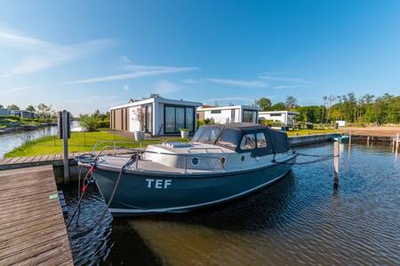 Boat at a jetty in front of a holiday home at the EuroParcs Veluwemeer holiday park