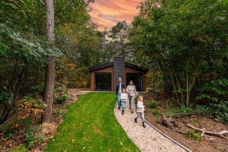 Family walks in front of a chalet at the EuroParcs de Wiltzangh holiday park