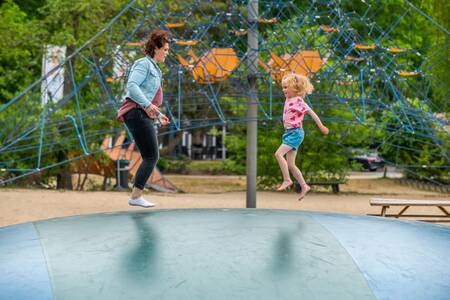 Mother and child jump on the air trampoline in a playground at the EuroParcs de Zanding holiday park