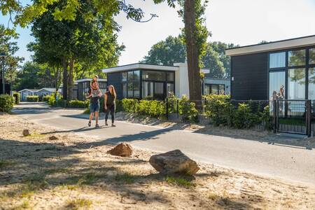 The family walks in front of a few holiday homes at the Europarcs Bad Hoophuizen holiday park