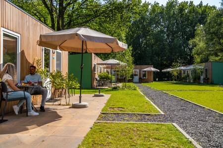 A couple is sitting in the garden of a chalet at the Europarcs Het Amsterdamse Bos holiday park