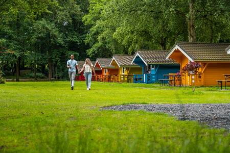 A couple walks in front of chalets at the Europarcs Het Amsterdamse Bos holiday park