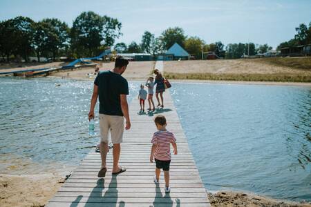 Family walks on a jetty through the recreational lake of Holiday Park Wilsumer Berge