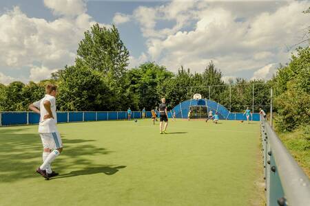 Children playing football on the all-weather sports field of holiday park Mölke