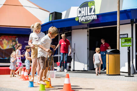 Children play in front of the Chiliz playroom at the Kampeerdorp de Zandstuve holiday park