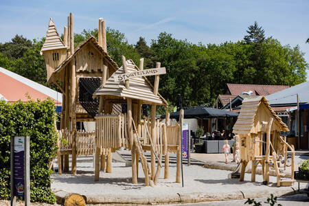 A playground with wooden play equipment at the Kampeerdorp de Zandstuve holiday park