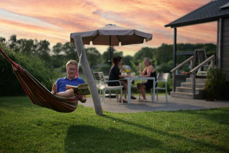 Man in a hammock in the garden of a lodge at the Krieghuusbelten holiday park