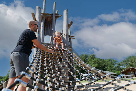 Man together with a small child on a playground equipment on Krieghuusbelten