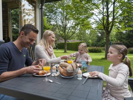 Family breakfast in the garden of a holiday home at Landal Aelderholt holiday park