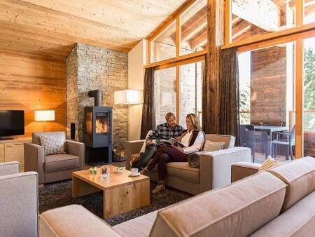 2 People in the living room with wood stove of an apartment at Landal Alpine Lodge Lenzerheide