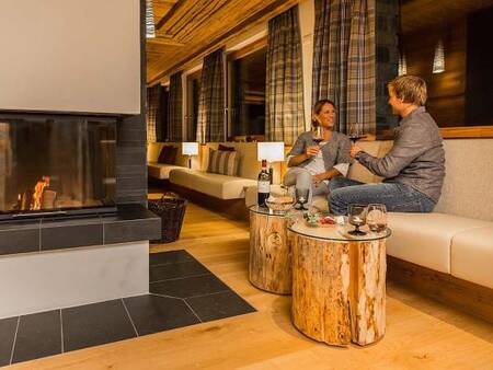 Couple enjoy a glass of wine by the fire in a restaurant at Landal Alpine Lodge Lenzerheide