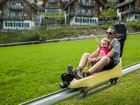 Father and daughter tobogganing on the toboggan run of Landal Alpen Chalets Katschberg