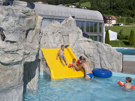 Children slide down the slide in the paddling pool at Landal Alpen Resort Vierwaldstättersee