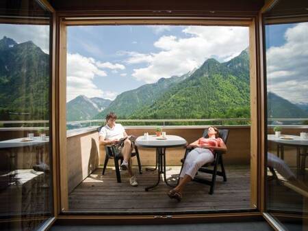 2 people relax on the balcony of an apartment at Landal Alpen Chalet Matin
