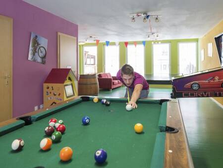 A boy playing billiards in the amusement arcade at the Landal Bad Kleinkirchheim holiday park