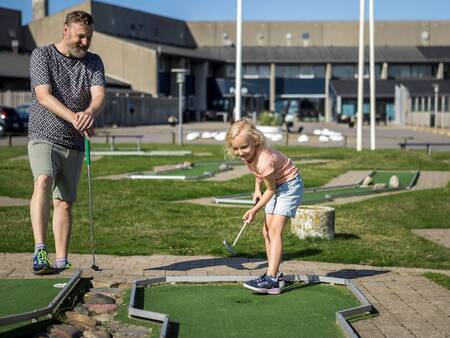 Father and daughter playing mini golf at Landal Strandappartementen Fyrklit