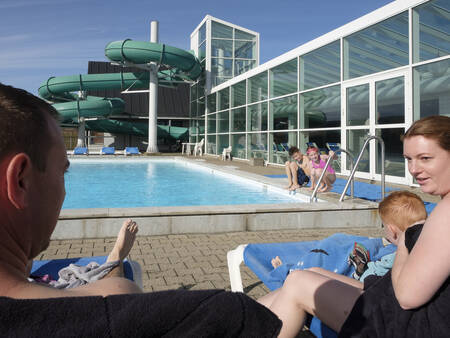 Family on sun loungers by the outdoor pool at the Landal Beach Park Grønhøj Strand holiday park